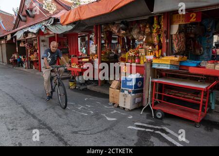 George Town, Penang/Malaysia - Jul 19 2018: Ein alter Mann Fahrrad in der Nähe des Standes verkaufen joss Stick, joss Papier an Goddess of Mercy Tempel. Stockfoto