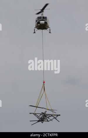 G-UHGB, eine Bell 205A-1, die vom Luftfahrtspezialisten Heli-Lift Services während der Pylonen-Umbauarbeiten auf den Renfrewshire Heights in Inverclyde, Schottland, betrieben wird. Die Pylone werden am Hang abgesetzt und vor Ort aufgebrochen, dann mit dem Hubschrauber zu einem Rückgabeort transportiert, wo das Metall dann auf Lastwagen verladen und schließlich auf der Straße bewegt wird. Stockfoto