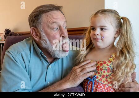 3 Jahre alte Lily, die mit Opa Horton albern handelt Stockfoto