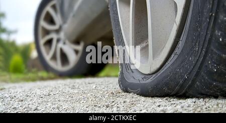 Nahaufnahme des flachen Hinterreifens am Fahrzeug. Das rechte hintere zerbrochene Weel. Beschädigte Hinterräder auf dem Parkplatz. Stockfoto
