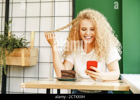 Attraktive blonde Frau sitzt im Café und mit ihrem Handy Telefon Stockfoto