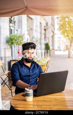 Junger erfolgreicher Geschäftsmann, der im Café im Freien arbeitet. Stockfoto