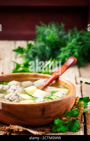 Hausgemachte Suppe mit putenfleischbällchen, Kartoffeln und Petersilie in Holzschüssel, rustikaler Stil, selektiver Fokus Stockfoto