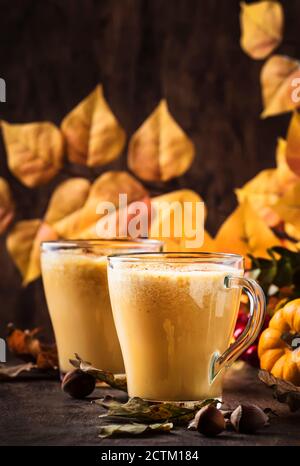 Kürbis gewürzter Latte oder Kaffee in Glas Tasse auf Vintage Holztisch. Heißes Getränk im Herbst oder Winter Stockfoto