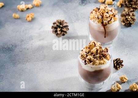 Kalte Schokolade Dessert mit Schlagsahne, Popcorn und Karamell Topping in Gläsern auf beigem Hintergrund, Platz für Text Stockfoto