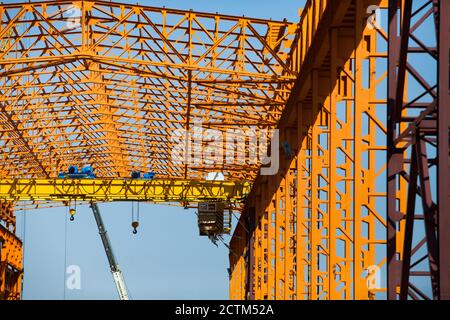 Kostanay/Kasachstan - Mai 14 2012: Bau eines neuen Fabrikgebäudes mit orangefarbener Stahlkonstruktion. Gelbe Krane mit zwei Haken. Stockfoto