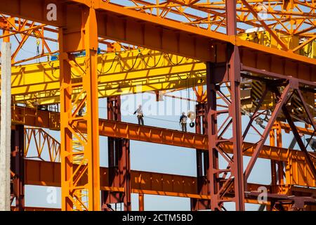 Kostanay/Kasachstan - Mai 14 2012: Bau eines neuen Fabrikgebäudes mit orangefarbener Metallstruktur. Zwei Höhenarbeiter (Industriekletterer) mit einem Stockfoto