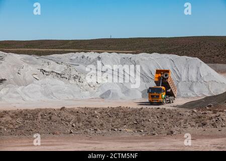 Mynaral/Kasachstan - April 23 2012: Blocklagerung von Rohstoffen in der Zementanlage von Jambyl. Mineralienhaufen (Klinker) und gelber Kipper. Stockfoto