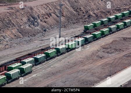 Güterbahnterminal. Eisenbahnwaggons auf Schiene. Grüne und braune Eisenbahnwaggons in der Wüste. Schienengüterverkehr. Stockfoto