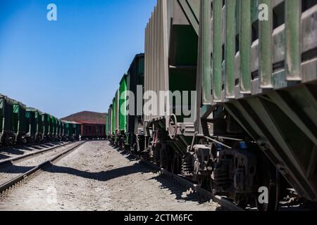 Mynaral/Kasachstan - April 23 2012: Zementwerk Jambyl Zement. Güterbahnterminal. Nahaufnahme von Eisenbahnwaggons mit Schienen am blauen Himmel in der Wüste. Stockfoto