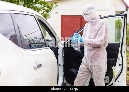 Mann mit Schutzkleidung, Handschuhen, OP-Maske und Gesichtsschutz, der Covid-19 Coronavirus an einem anderen Mann im Auto testet. Stockfoto