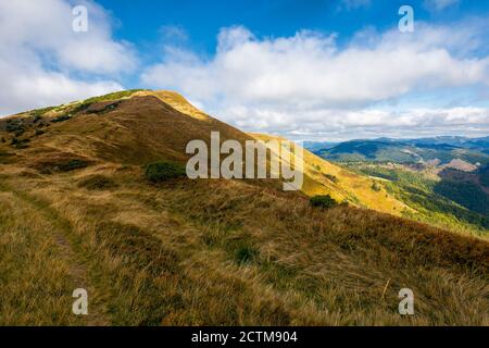 Berglandschaft im Herbst. Trockenes buntes Gras auf den Hügeln. Grat hinter dem fernen Tal. Blick von der Spitze eines Hügels. Wolken am Himmel. Synevi Stockfoto