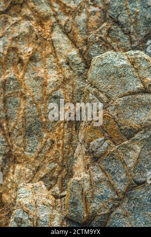 Nahaufnahme hell leuchtend orange braun gelb Stein Felsen schäbig Klippe Risse Textur Berge. Konzept der Geologie, Schönheit Kraft in der Natur. Natürlich Stockfoto