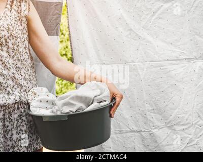 Schöne Gastgeberin hängt Bettwäsche. Sonniger Tag Stockfoto