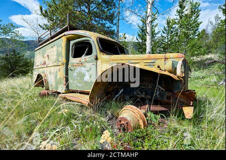 Altes rostiger Wrack eines LKW aus alten Kriegszeiten in einem Wald- und Grasgebiet in der Nähe von Chilco River, British Columbia, Kanada, Nordamerika Stockfoto