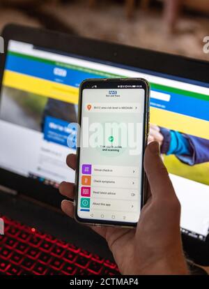 Poole, Großbritannien. Donnerstag, 24. September 2020. Ein Mann installiert die neue NHS Test and Trace App auf einem Smartphone. Die NHS-Website auf einem Laptop dahinter. Erster Tag der Einführung der neuen Tracing-App COVID-19. Kredit: Thomas Faull/Alamy Live Nachrichten Stockfoto