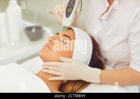 Frau, die Ultraschall-Gerät Gesichtsreinigung im Schönheitssalon Stockfoto