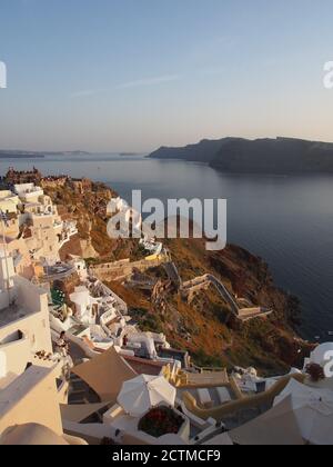 Massen von Touristen beobachten den Sonnenuntergang von der Burg von Agios Nikolaos mit Nea Kameni Insel am Horizont, Oia, Santorini Stockfoto