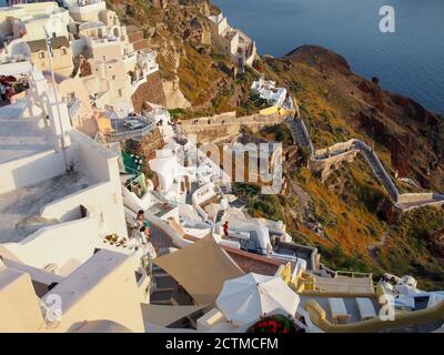 Massen von Touristen, die den Sonnenuntergang von Höhlenhäusern und Hotels der Caldera Oia, Santorini beobachten Stockfoto