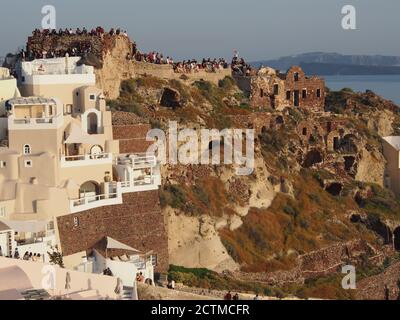 Massen von Touristen beobachten den Sonnenuntergang von der Burg von Agios Nikolaos, Oia, Santorini Stockfoto