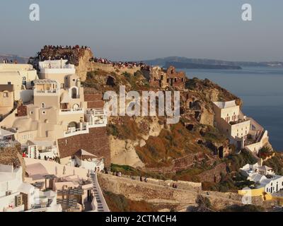 Massen von Touristen beobachten den Sonnenuntergang von der Burg von Agios Nikolaos, Oia, Santorini Stockfoto