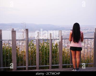 Afro-asiatische Frau von hinten betrachtet eine Landschaft mit einem Panoramablick Stockfoto