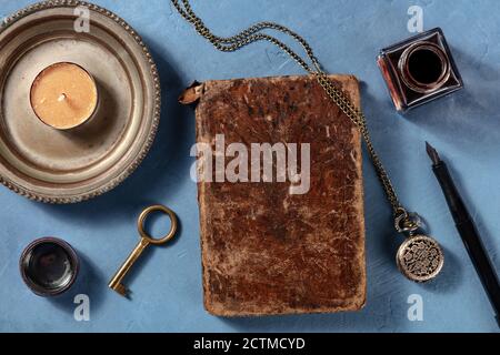 Ein altes Notizbuch mit Tintenstift, von oben mit anderen Vintage-Objekten aufgenommen, ein flaches lag auf blauem Hintergrund Stockfoto