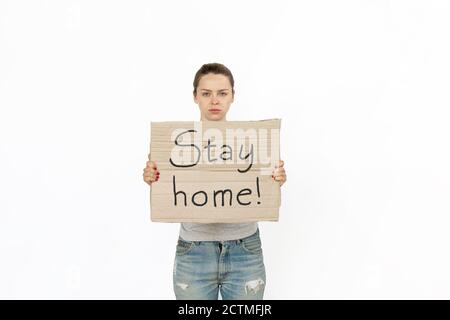 Bleib zu Hause. Junge Frau protestiert mit Schild isoliert auf weißem Studio Hintergrund. Aktivismus, aktive soziale Position, Protest, tatsächliche Probleme. Treffen gegen die Ausbreitung des Coronavirus. Gesundheitswesen. Stockfoto