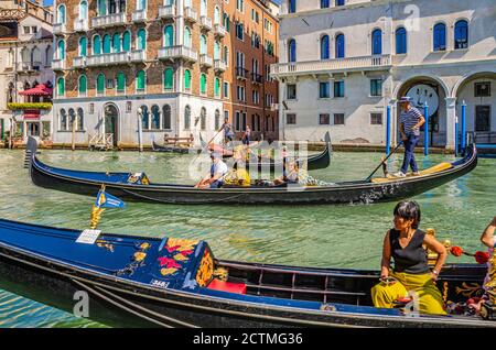 Venedig, Italien, 13. September 2019: Gondoliere und Touristen auf Gondel traditionelle Boot Segeln auf dem Wasser des Canal Grande Wasserstraße mit venezianischer Architektur typischen bunten Gebäuden Hintergrund Stockfoto