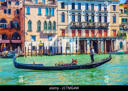 Venedig, Italien, 13. September 2019: Gondoliere und Touristen auf Gondel traditionelle Boot Segeln auf dem Wasser des Canal Grande Wasserstraße mit venezianischer Architektur typischen bunten Gebäuden Hintergrund Stockfoto