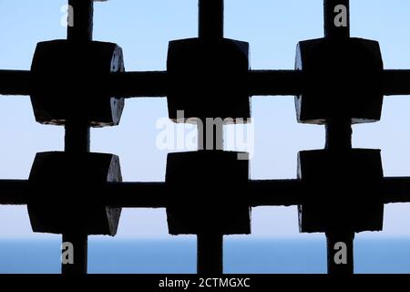 Blick durch altes Metallgitter auf Meer und Himmel. Lattiked Fenster der mittelalterlichen Burg Stockfoto