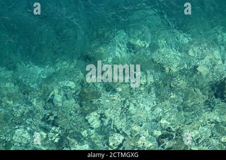 Azure Wasser Textur, transparente Meeresoberfläche mit einem felsigen Boden. Luftaufnahme, natürlicher blauer Hintergrund Stockfoto