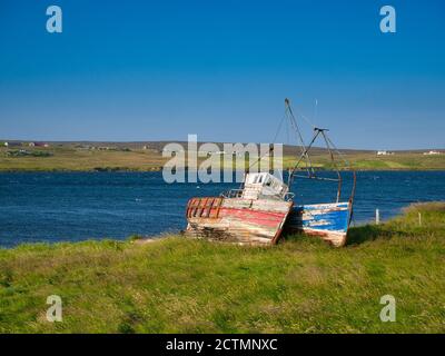 Alte, verlassene hölzerne Fischerboote am Ufer von Mid Yell Voe bei Mid Yell, auf der Insel Yell, Shetland, Schottland, Großbritannien Stockfoto