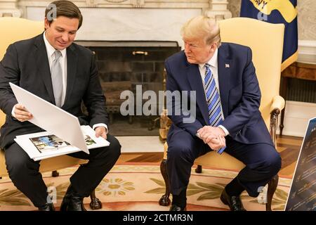 Präsident Trump trifft sich mit dem Gouverneur von Florida. Präsident Donald J. Trump sieht sich Diagramme und Fotos während seines Treffens mit Florida Gov an. Ron DeSantis Dienstag, 28. April 2020, im Oval Office des Weißen Hauses. Stockfoto