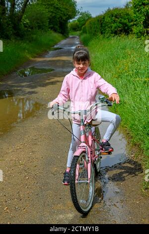 Junges Mädchen auf dem Fahrrad in einer Landstraße Stockfoto