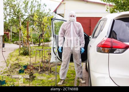 Mann mit Schutzkleidung, Handschuhen, OP-Maske und Gesichtsschutz, der Covid-19 Coronavirus an einem anderen Mann im Auto testet. Stockfoto