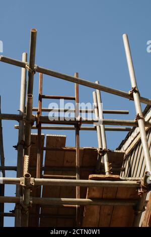 Blick vom Boden auf Gerüste zwischen zwei Häusern, die die Pole, Kupplungen und Leiter zeigen Stockfoto