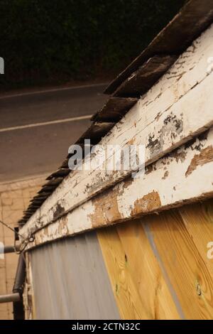 Eine Nahaufnahme von Gerüsten, die die Länge eines Lastkahnes auf einem alten Holzverkleidungs-Haus betrachten, das Reparaturen, Abschleifen und Neulackieren benötigt Stockfoto