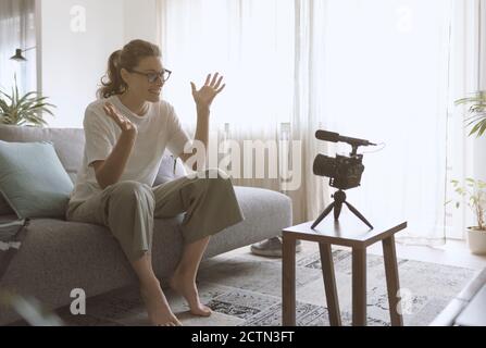 Professionelle Youtuberin und Vlogger sitzen auf der Couch zu Hause und nehmen ein Video für ihr Kanal-, Kommunikations- und Technologiekonzept auf Stockfoto