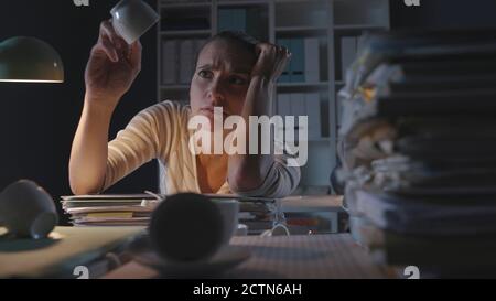 Frustriert Frau im Büro in der Nacht, hatte sie viele Tassen Kaffee und fühlt sich erschöpft, arbeiten Überstunden Konzept Stockfoto