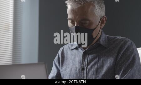 Professioneller Geschäftsmann, der während einer Coronavirus-Pandemie im Büro arbeitet, trägt er eine Gesichtsmaske Stockfoto