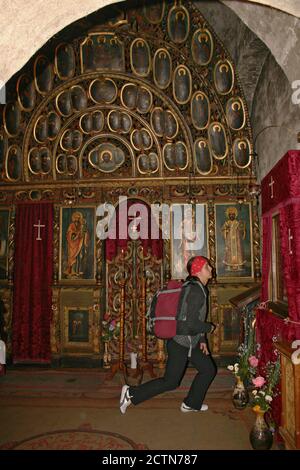 Junge Gläubige beten in der kleinen Kapelle im christlich-orthodoxen Bistrita Kloster im Kreis Neamt, Rumänien. Ikonostase aus dem 18. Jahrhundert. Stockfoto