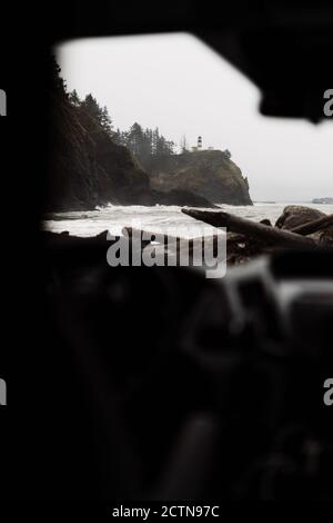 Blick von innen auf das Auto, das in der Nähe des rauhen felsigen Ozeans geparkt ist Küste mit stürmisch winkenden Wasser bei kaltem bewölktem Wetter in USA Stockfoto