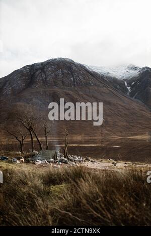 Erstaunliche Landschaft des Campingplatzes mit Lagerfeuer in gebirgigen gelegen Terrain im Herbst in den schottischen Highlands Stockfoto