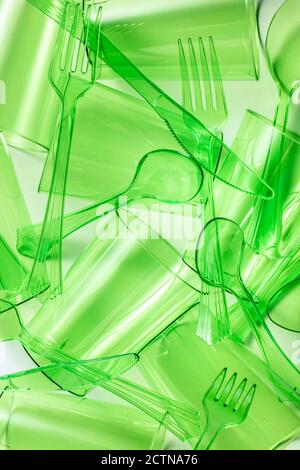 Draufsicht Zusammensetzung der leuchtend grünen transparenten Kunststoff Tassen mit Gabeln und Löffel und Messer auf weißem Hintergrund platziert