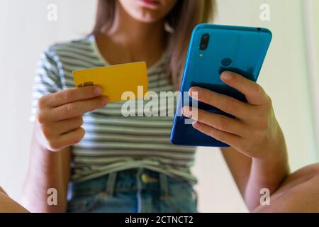 Von unten von unkenntlich Ernte weiblich sitzen zu Hause und Zahlung mit Plastikkarte über Handy beim Online-Shopping Stockfoto