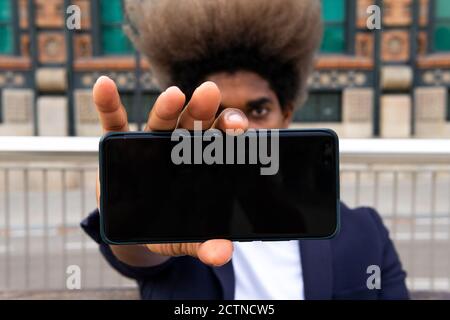 Afrikanischer Mann in Anzug zeigt sein Handy an die Kamera Stockfoto