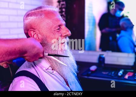 Männliche Friseur schneiden Haare Hipster Senior Client - Seite Blick auf junge Friseurin arbeiten in Friseursalon - Frisur Beruf Konzept Stockfoto