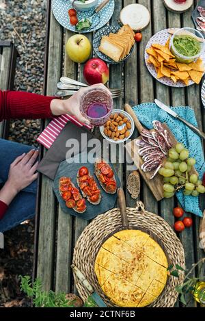 Hoher Winkel von nicht erkennbaren weiblichen Freundinnen, die am Holztisch sitzen Im Wald und Essen leckeres Essen während Picknick in Valle Del Jerte im Sommer Stockfoto