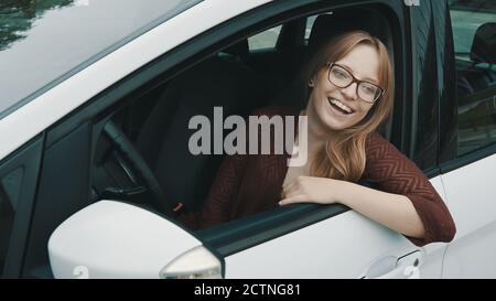 Nahaufnahme, Gesichtsausdruck einer jungen kaukasischen Frau, die auf dem Fahrersitz sitzt und durch das Fenster schaut, während sie ihre Hand ausruht. Hochwertige Fotos Stockfoto